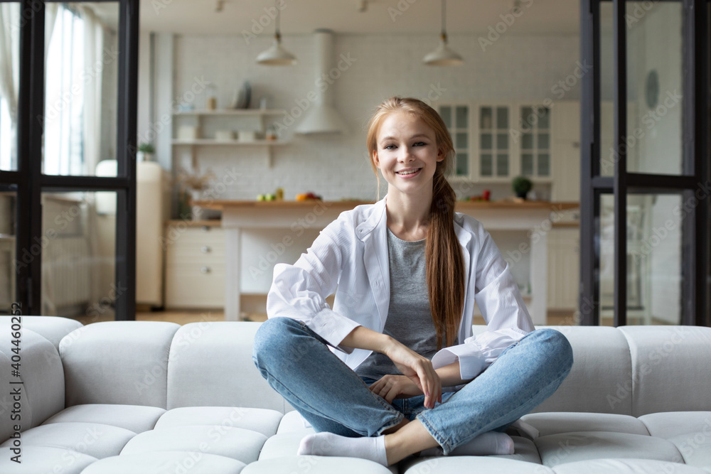 Smiling positive woman sitting on cozy couch resting at home.