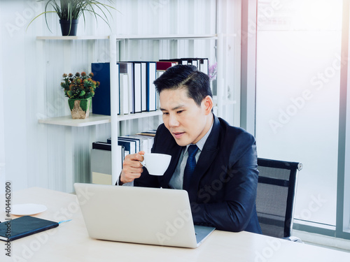 Asian handsome businessman in suit working with laptop computer on desk in office.