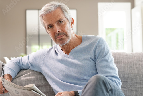 Attractive senior man relaxing at home reading newspaper