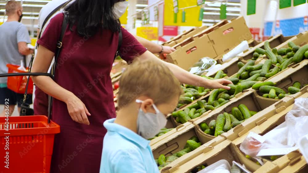 A mother and child in medical masks are shopping in a supermarket. A woman and a little boy in the vegetable department. Social distance the second world war the time of a pandemic. A mother and child in medical masks are shopping in a supermarket. A woman and a little boy in the vegetable department. Social distance the second world war the time of a pandemic.
