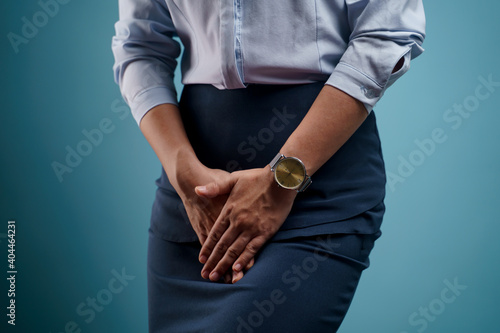 Close up shot of woman holding hands pressing her crotch.