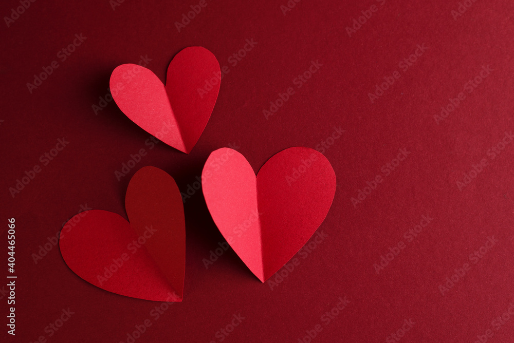 Red paper Hearts on a dark red background. Valentines Day monochrome concept card.