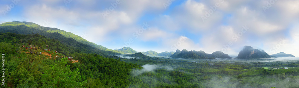 Panorama of beautiful rural countryside and mountains landscape with fog on cloudy blue sky background in Phatthalung province, Southern of Thailand. Natural outdoor travel background concept