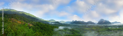 Panorama of beautiful rural countryside and mountains landscape with fog on cloudy blue sky background in Phatthalung province, Southern of Thailand. Natural outdoor travel background concept