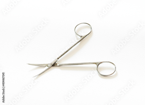 Tiny metal scissors on white table.