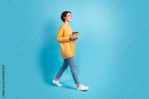 Full length body side profile photo of girl bob hair carrying coffee holder with two beverages isolated on bright blue color background