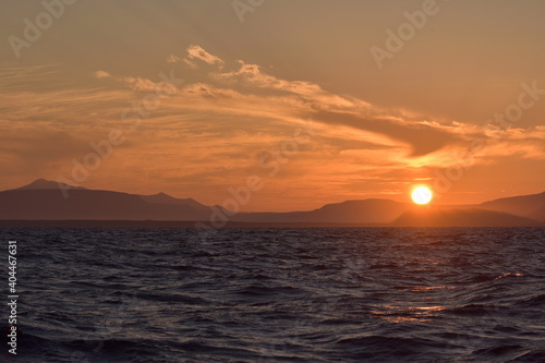 Colorfull sunset over mountanous coast seen from the sea. Expedition to the Kuril islands to the south from Kamchatka peninsula.