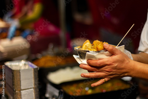 Hands of a person with a ready to eat food box or tasting in a brown cardboard box at a street food market. Brick Lane, London