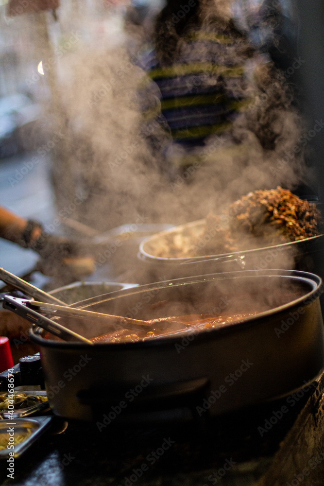 Street food, barbecuing on a hot grill with fire and smoke, thai food, vegetables and meat cooked for taking out. Brick Lane Food Market Street food, barbecuing on a hot grill with fire and smoke, thai food, vegetables and meat cooked for taking out. Brick Lane Food Market