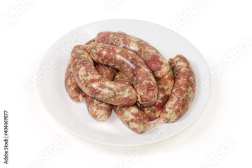 Uncooked homemade pork sausages on white dish, semifinished