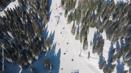 Aerial view of ski slopes and trees, ski lift and recreational skiers, sunny day covered in snow on Mountain Kopaonik photo