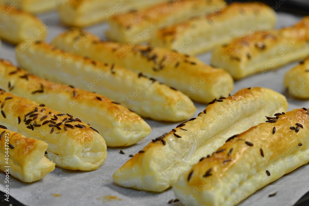 Baked salty sticks with salt and cumin. Golden baked savory pastry. Home baking appetizers. Crispy savory pastry on a baking sheet. Baked salty sticks with salt and cumin. Golden baked savory pastry. Home baking appetizers. Crispy savory pastry on a baking sheet.