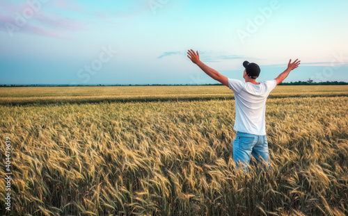 Male farmer standing in a wheat field during sunset. Man Enjoys Nature © es0lex