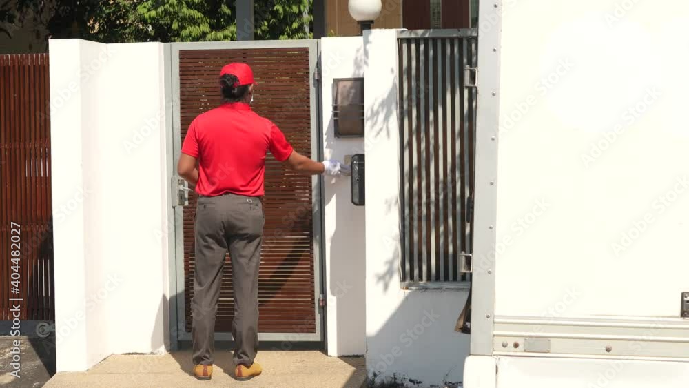 The safe delivery concept, A courier in a red uniform with protective mask and gloves take the parcel to the customer home in quarantine. The safe delivery concept, A courier in a red uniform with protective mask and gloves take the parcel to the customer home in quarantine.