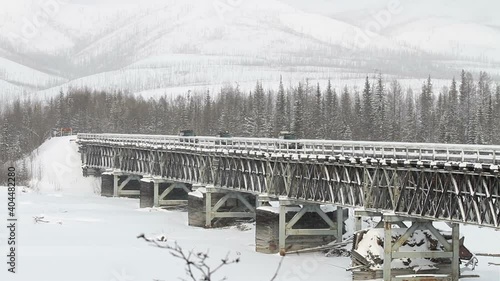 Offroad cars crossing a bridge in Siberia. Arctic expedition. Bridge. Russia. wooden bridge Siberia. Road trip in winter season. Winter blizzar in Russia, Yakutia. Explore the world concept. Cold photo