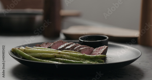 sliced beef steak with asparagus on black plate on concrete countertop photo