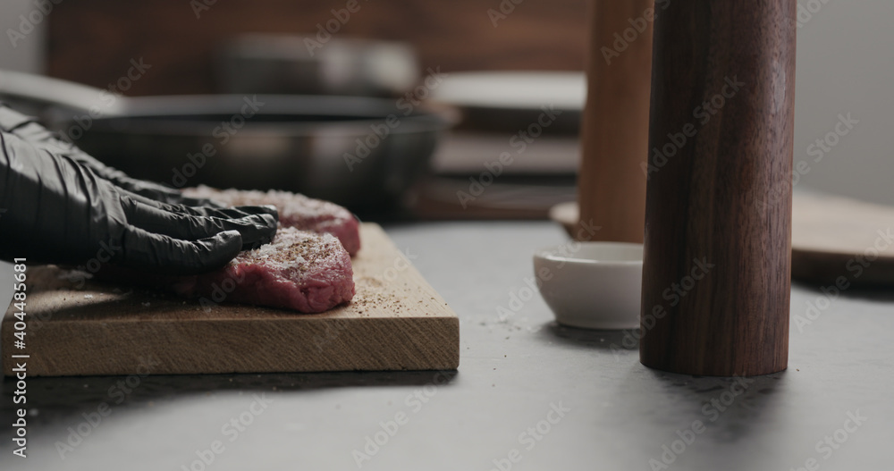 Ταπετσαρία man rub seasoning into raw beef steak on oak board