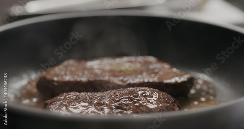 two beef steak pieces frying on nonstick pan