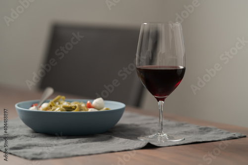 Red wine in thin wine glass with pasta in blue bowl