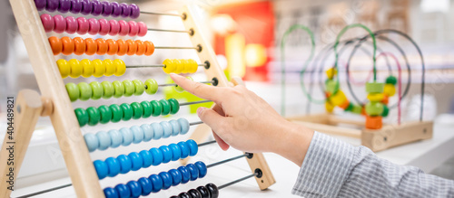 Tableau sur toile Male hand calculating with beads on wooden rainbow abacus for number calculation