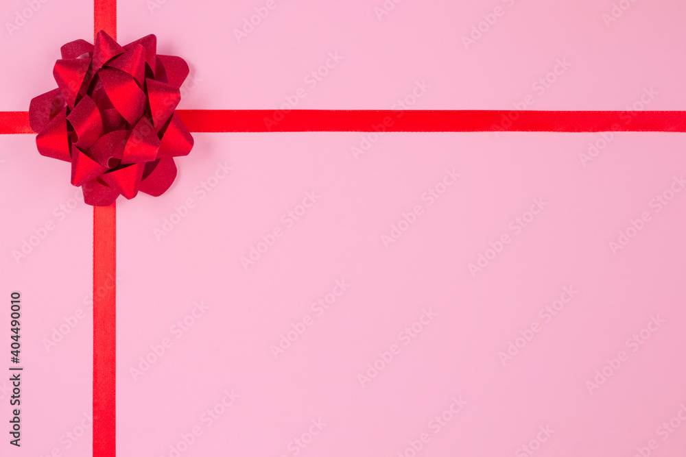 Flat lay composition with decorative red ribbon bow on pink background with copy space for text. Giving presents concept. Greeting card or holidays sale background. Selective focus Flat lay composition with decorative red ribbon bow on pink background with copy space for text. Giving presents concept. Greeting card or holidays sale background. Selective focus