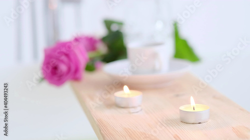 Beautiful spa setting with pink candle and flowers on wooden background. Concept of spa treatment in salon. Atmosphere of relax, serenity and pleasure. Luxury lifestyle.