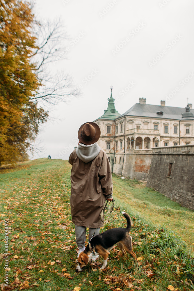 young woman with a dog walking near the old castle in autumn