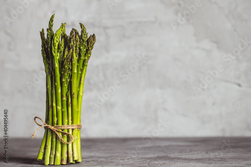 Fresh bunch of asparagus with smooth daylight on grey stone background/top view