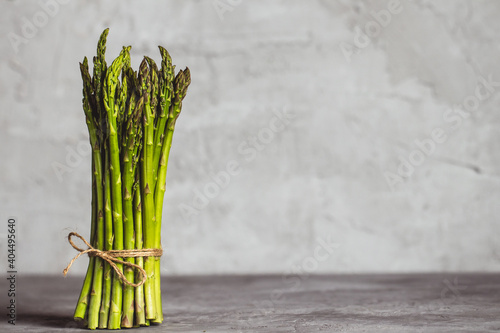 Fresh bunch of asparagus with smooth daylight on grey stone background top view