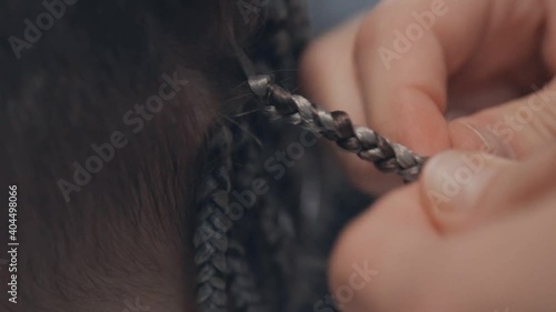 The master weaves braids from artificial hair.
