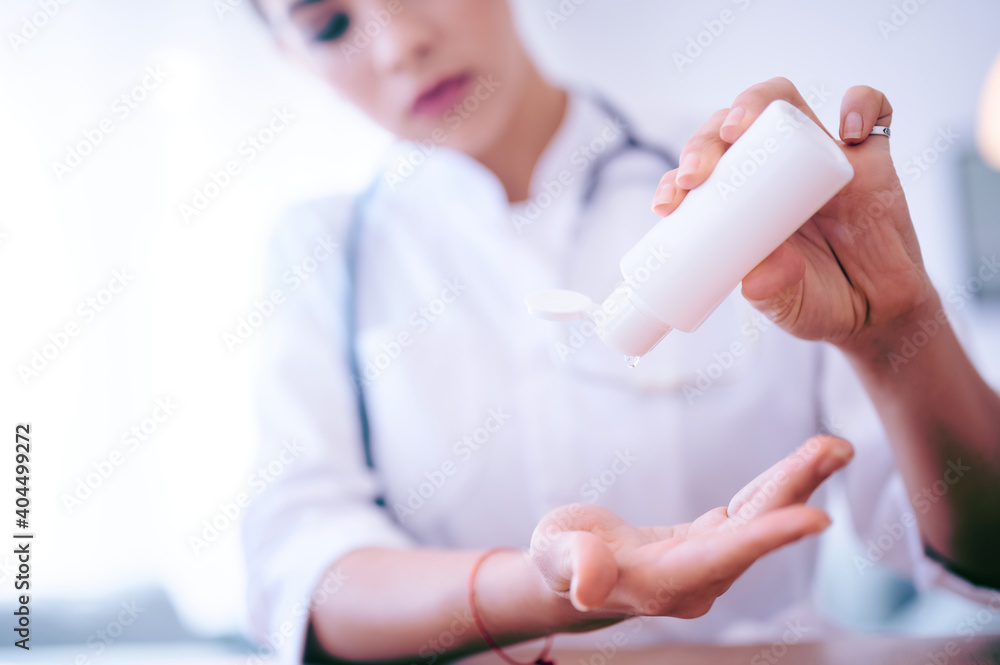 Young female doctor applies antiseptic gel before start working day. Hospital worker cleaning hands using liquid alcoholic sanitizer Young female doctor applies antiseptic gel before start working day. Hospital worker cleaning hands using liquid alcoholic sanitizer