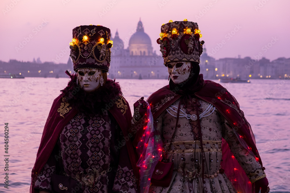 Venice, Italy - February 18, 2020: An unidentified couple in a carnival costume in front of Santa Maria della Salute, attends at the Carnival of Venice.