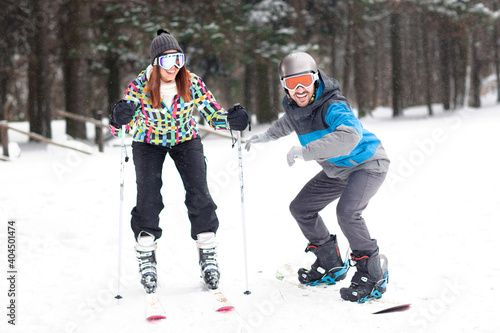 A guy on the snowboard and a girl on skis