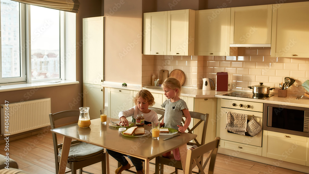 Little brother and sister having breakfast on their own in the morning at home. Adorable boy making a sandwich for himself Little brother and sister having breakfast on their own in the morning at home. Adorable boy making a sandwich for himself