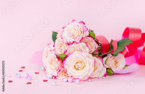 delicate bouquet of bushy peony roses with bright ribbons  pearls  feathers and hearts  on a pink background  the concept of congratulations on Valentine s day