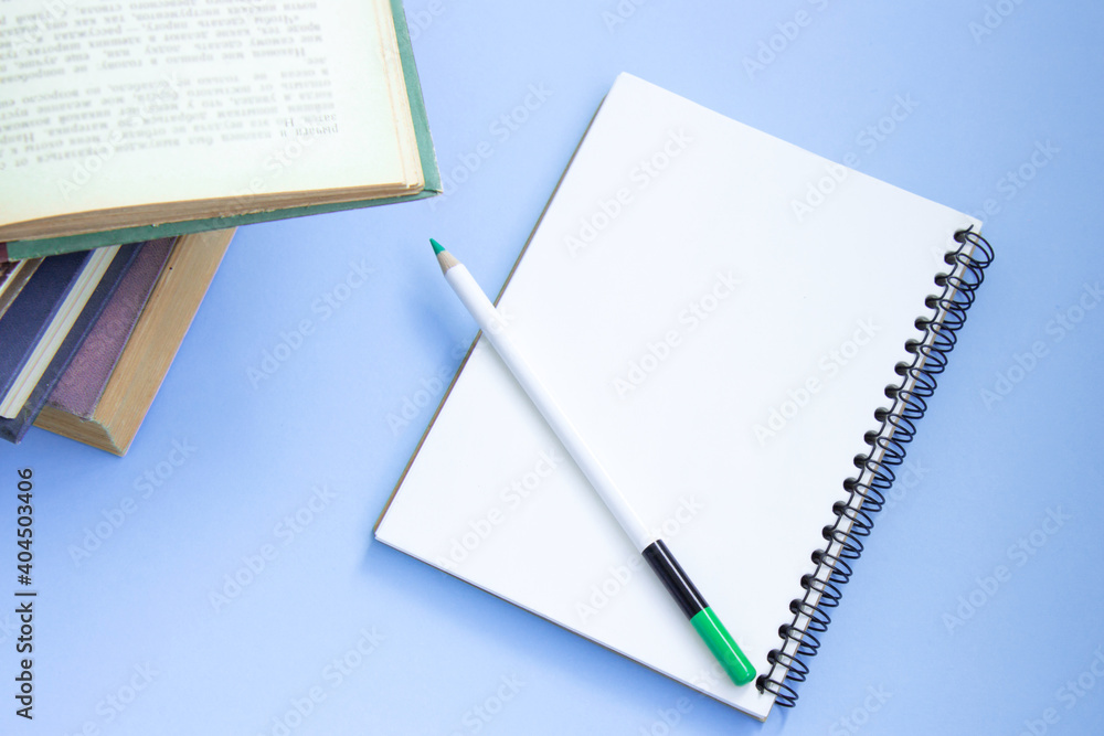 Stack of colorful old hardback books with open notebook and pencil. Back to school. Hardback books on violet background. Top view Stack of colorful old hardback books with open notebook and pencil. Back to school. Hardback books on violet background. Top view