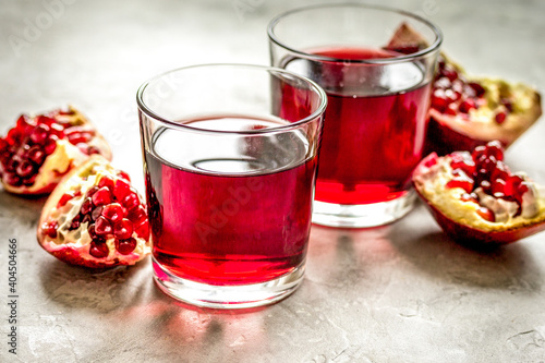 ripe pomergranate and glass of juice on table background