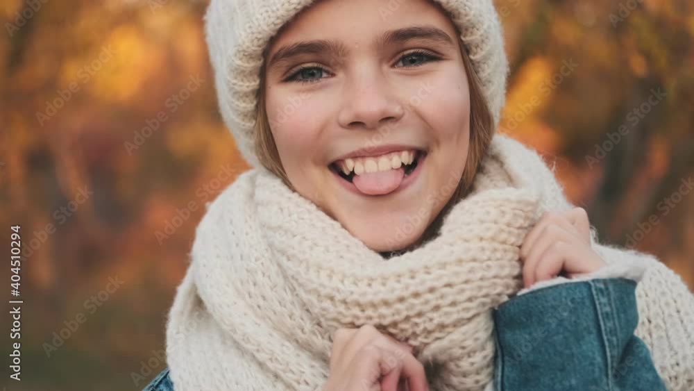 A cheerful young blonde girl is looking to the camera while walking in the park outside A cheerful young blonde girl is looking to the camera while walking in the park outside
