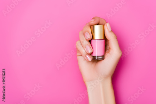 Wallpaper Mural top view of groomed female hand with vial of pastel nail polish on pink background Torontodigital.ca