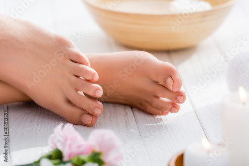 cropped view of female feet with pink pastel pedicure on white wooden surface  blurred foreground