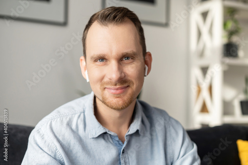 A head shot of a young happy man in casual shirt talking via video call, mentor, trainer conducts webinar, online class. Video meeting, virtual conference with an intelligent guy, webcam view
