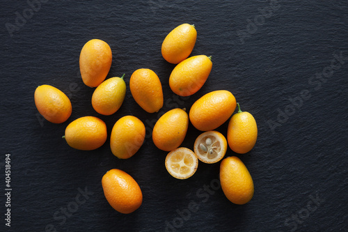 Group of Kumquats on a black stone background. Citrus fruits. View from above.
