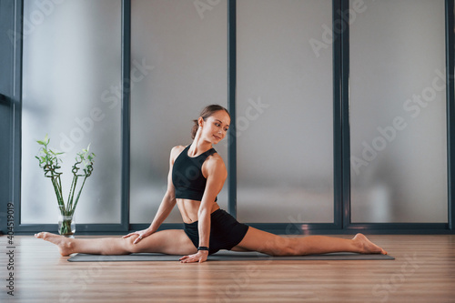 Good stretching. Young woman in sportive wear and with slim body have fitness yoga day indoors