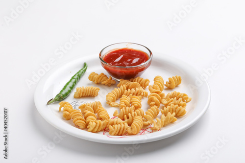Past and potato chips with tomato sauce in plate. crispy and spicy snack on white background