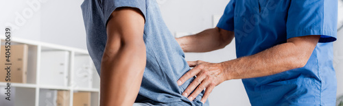 cropped view of mature chiropractor working with african american man, banner