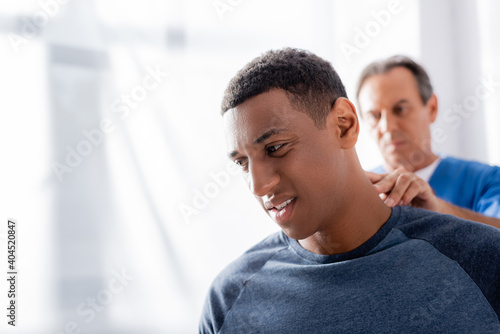 blurred therapist massaging african american patient in clinic