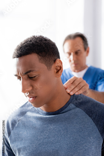 blurred chiropractor working with african american patient in clinic