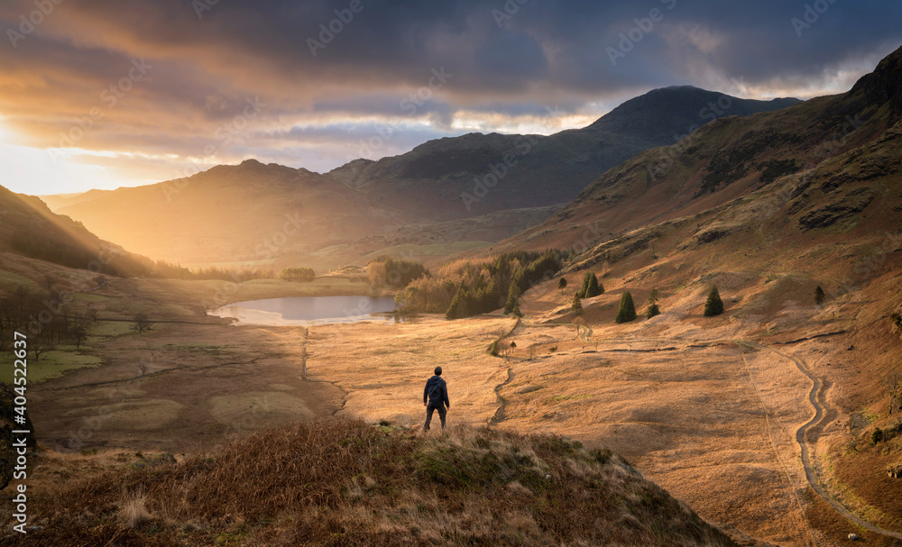 Lone figure surveying the valley as dawn breaks in the beautiful Lake District