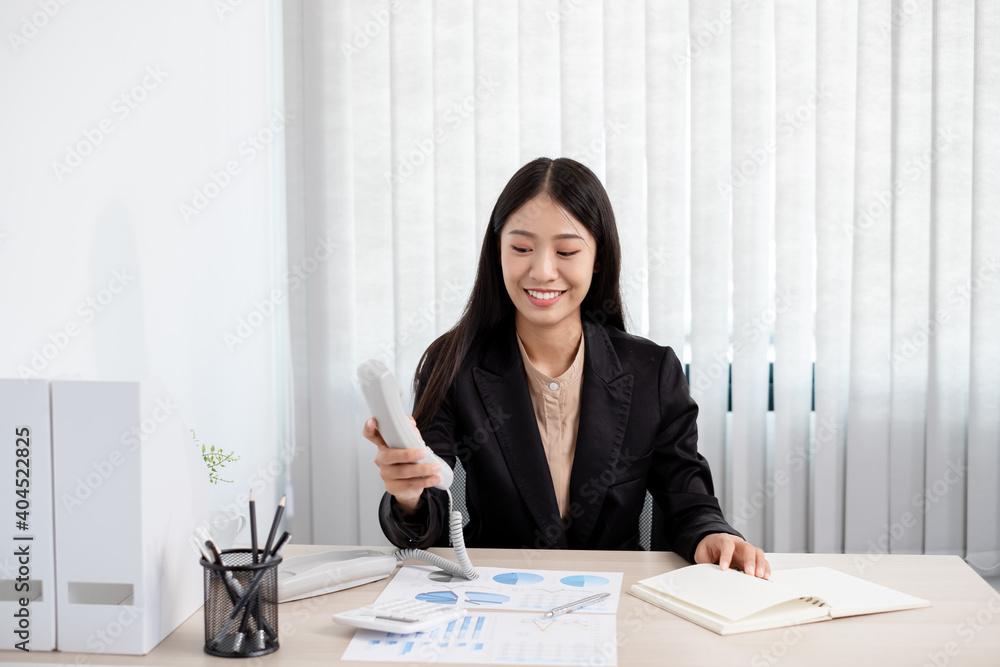 Asian businesswoman talking on the phone and working with a cheerful and happy smile while working at the office Asian businesswoman talking on the phone and working with a cheerful and happy smile while working at the office