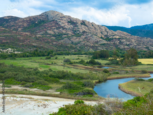 Panoramic view of the Desert des Agriates in the Balagne region of Corsica, the lush green river valley and the Etang de Foce with cloudy sky near Ostriconi Beach, Ile Rousse, Corsica, France. 
